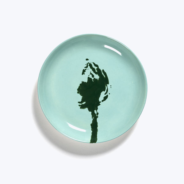 Abstract floral design on seafoam green ceramic plate, white background.