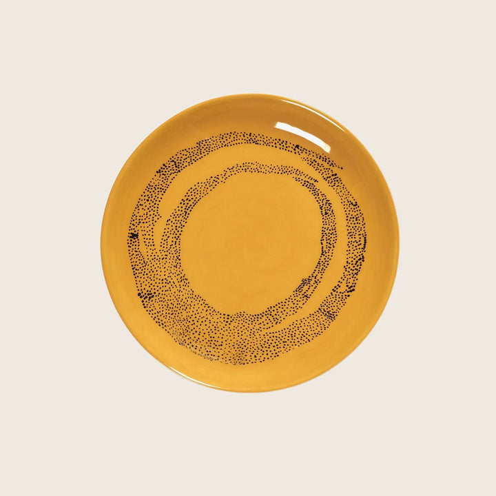 Yellow ceramic plate with black concentric dot pattern on white.