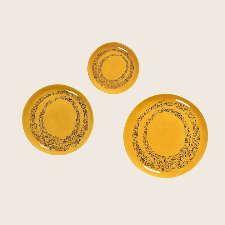 Three yellow plates with decorative pattern in varying sizes set