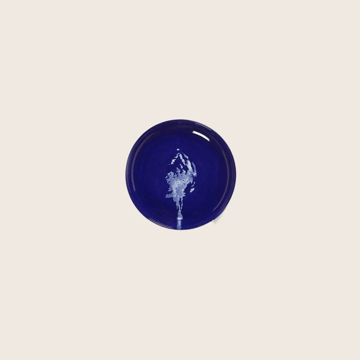 Blue ceramic bowl with white splash pattern on light background.