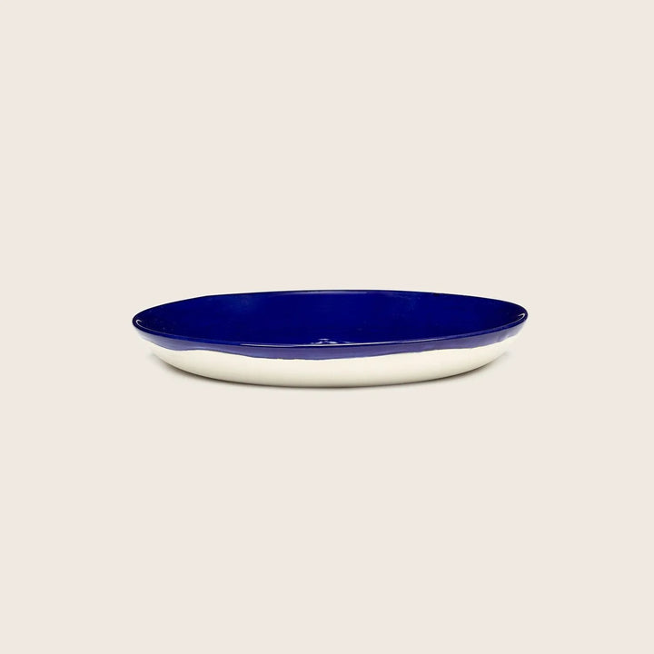 Oval serving dish with cream exterior and cobalt blue interior