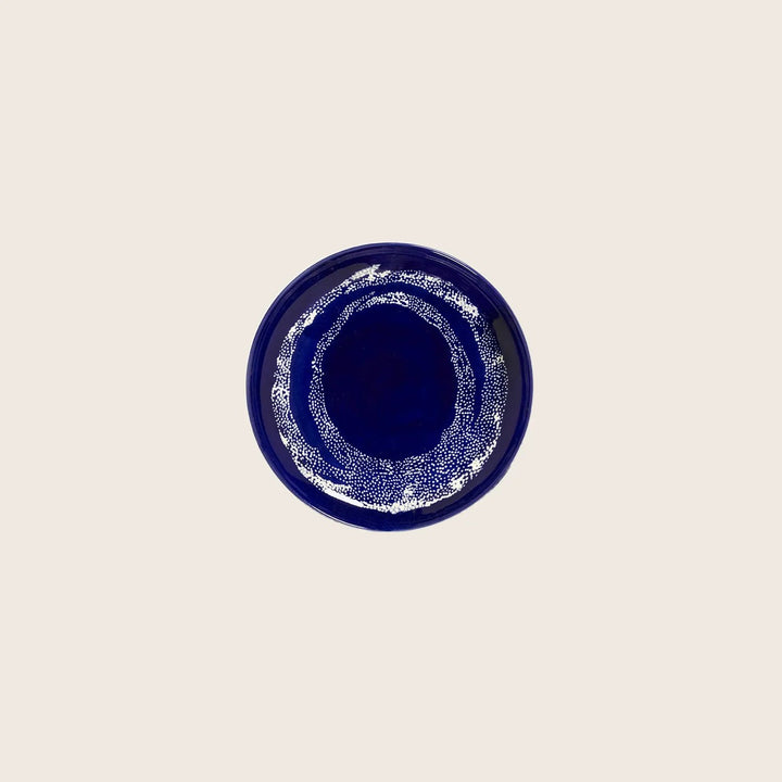 Dark blue glazed ceramic plate with concentric circle pattern design.