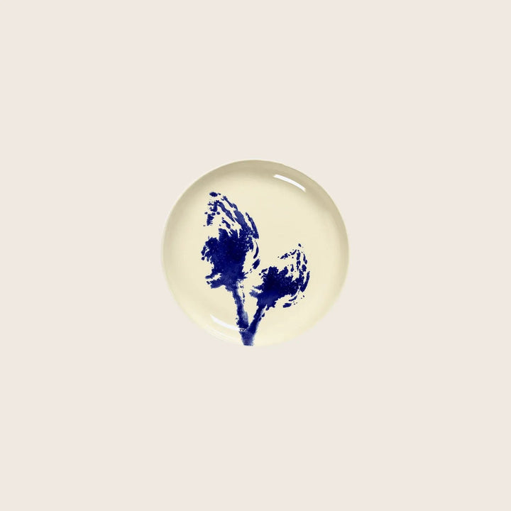 Blue inkblot pattern on round plate against white background.