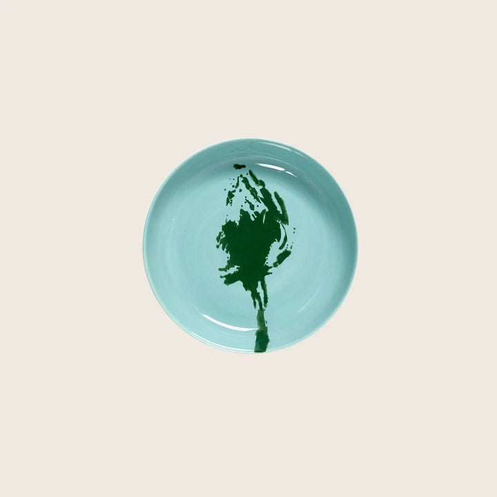 Round light blue plate with abstract dark green smear center.