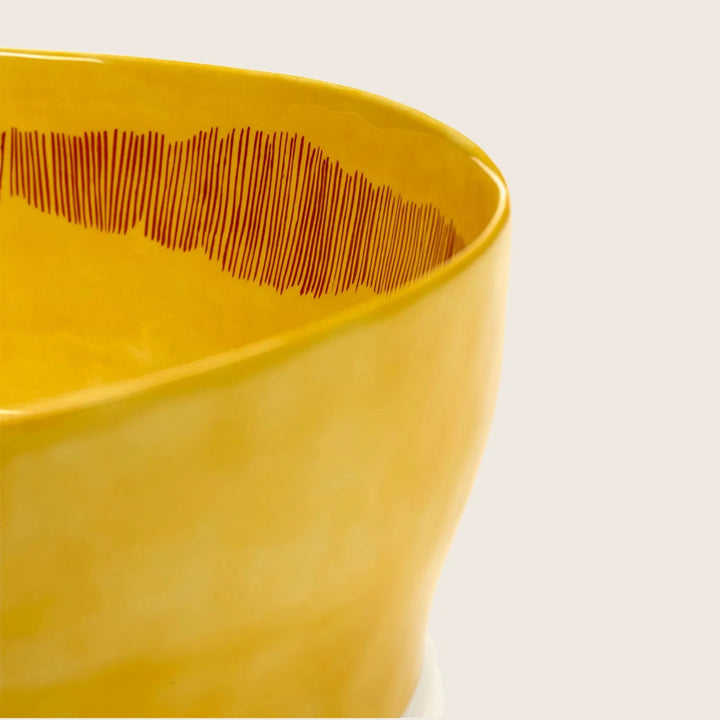Close-up of yellow bowl with decorative pattern on glossy surface.