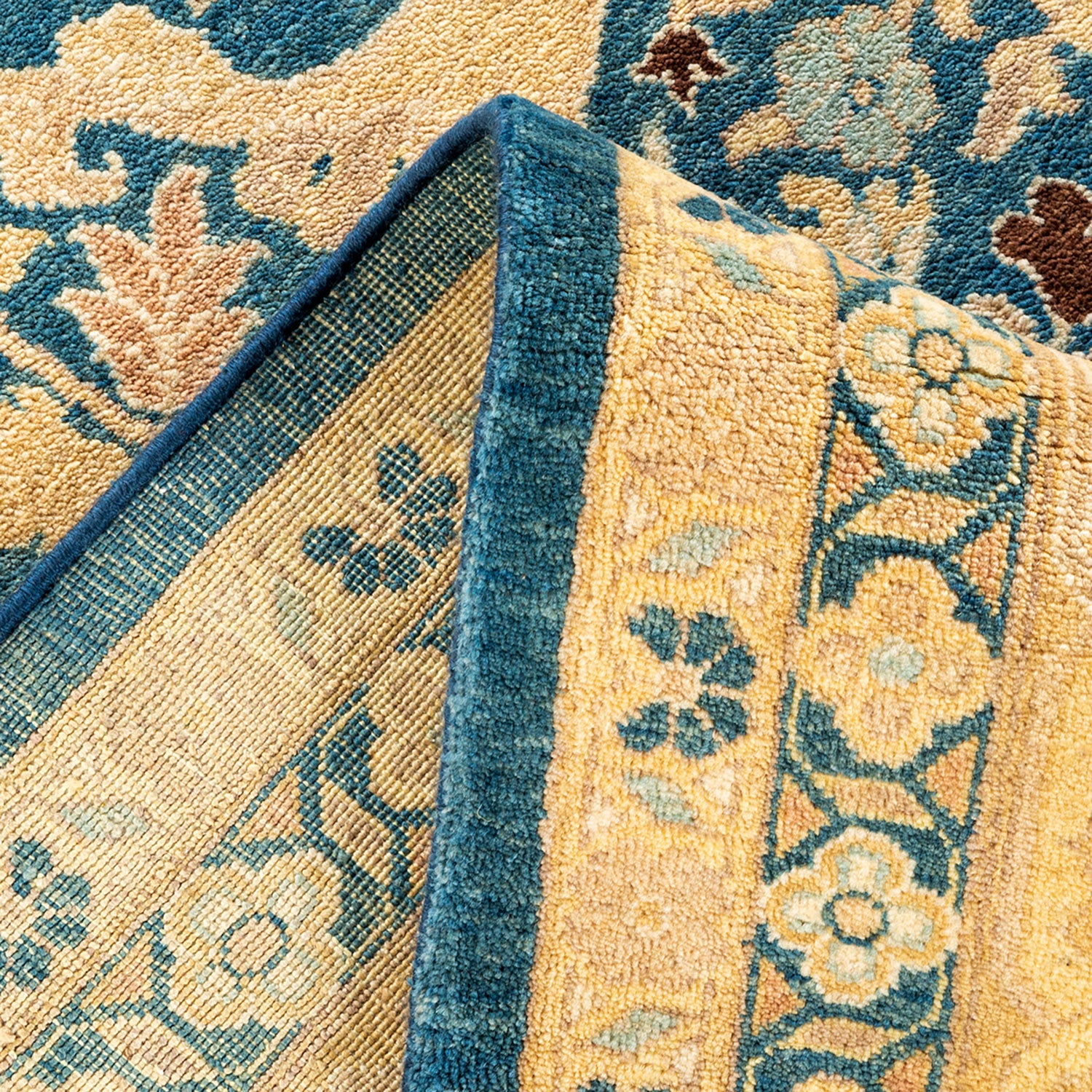 Close-up of folded carpet reveals intricate pattern and textured backing.