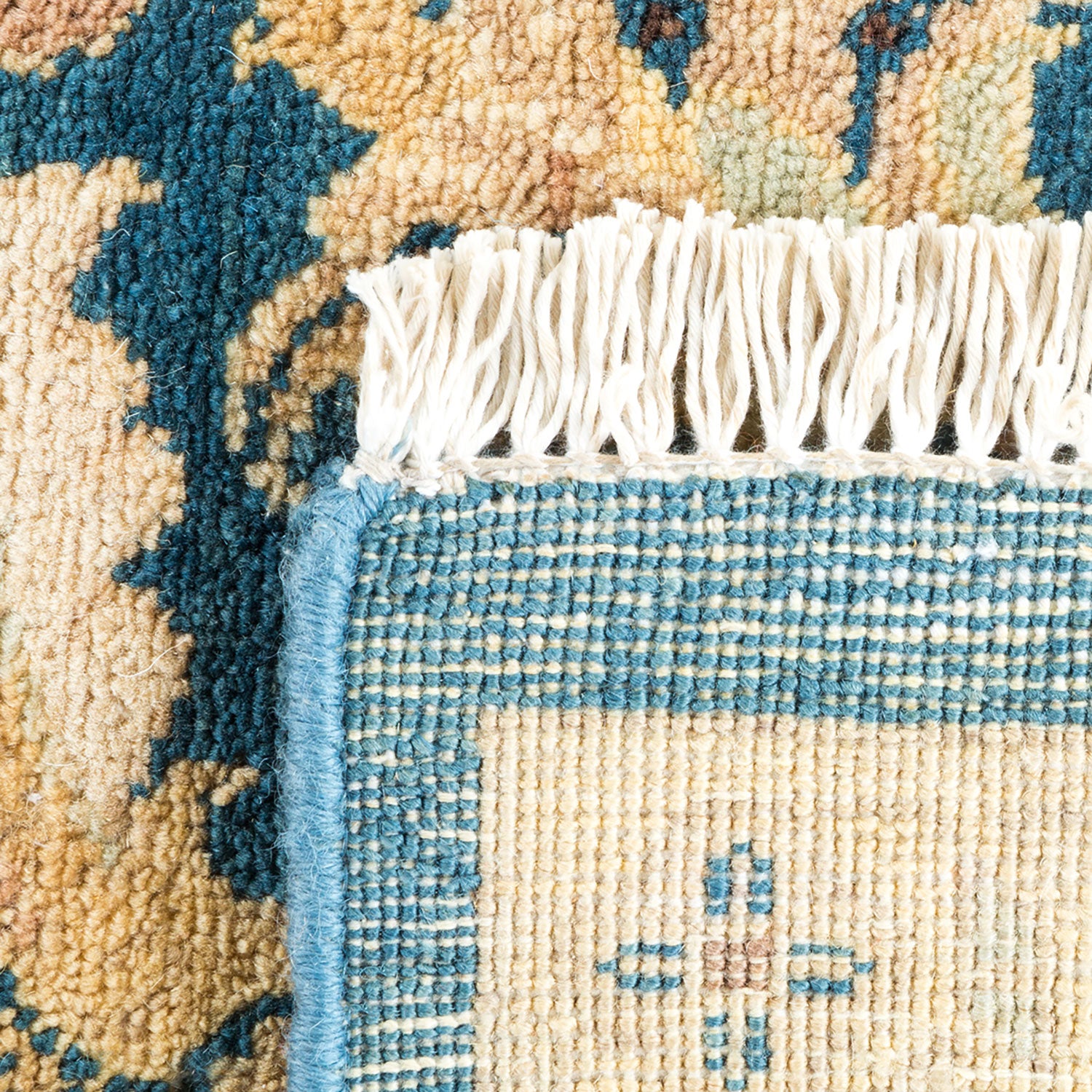 Close-up of a intricately woven rug with blue border and fringe.