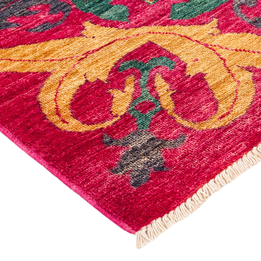 Close-up of a vibrant, symmetrical floral rug with fringe edge.
