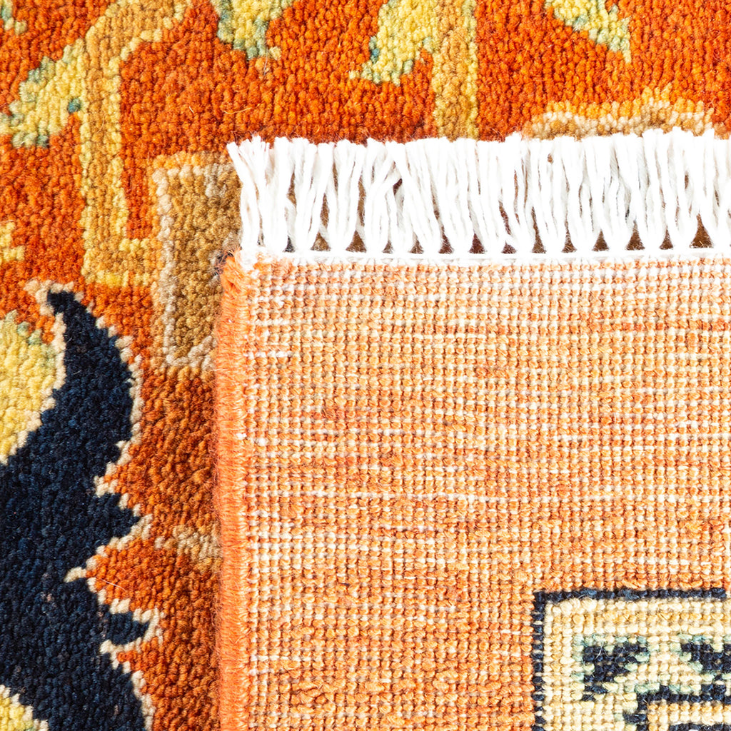 Close-up of a vibrant, intricately designed hand-woven rug with fringe.