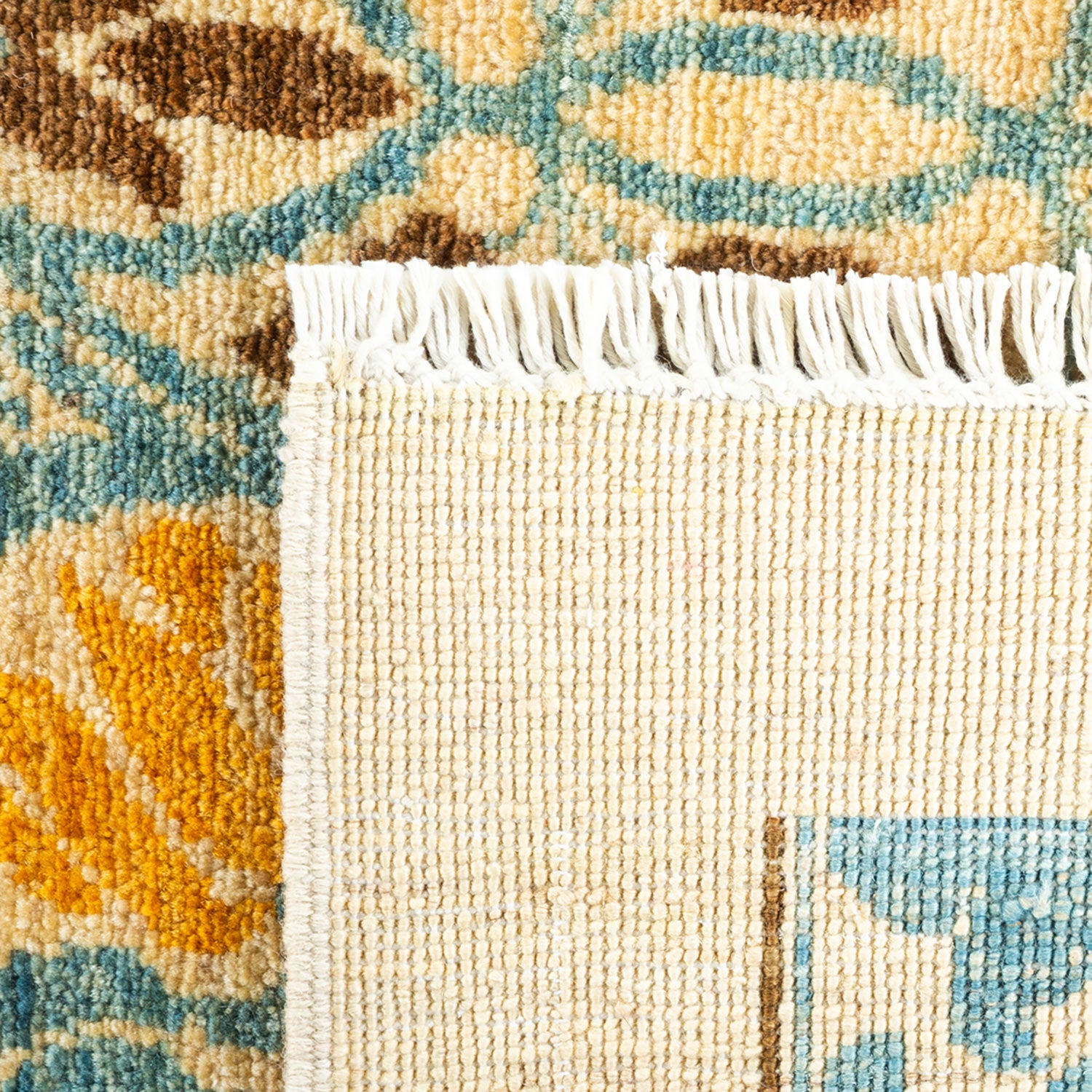 Close-up view of a ornate woven rug with fringe detail.