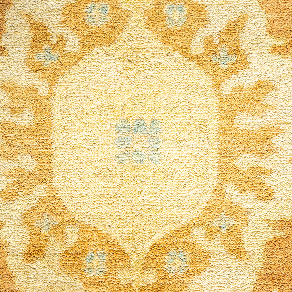 Close-up of a plush, golden yellow patterned carpet with floral-like motifs