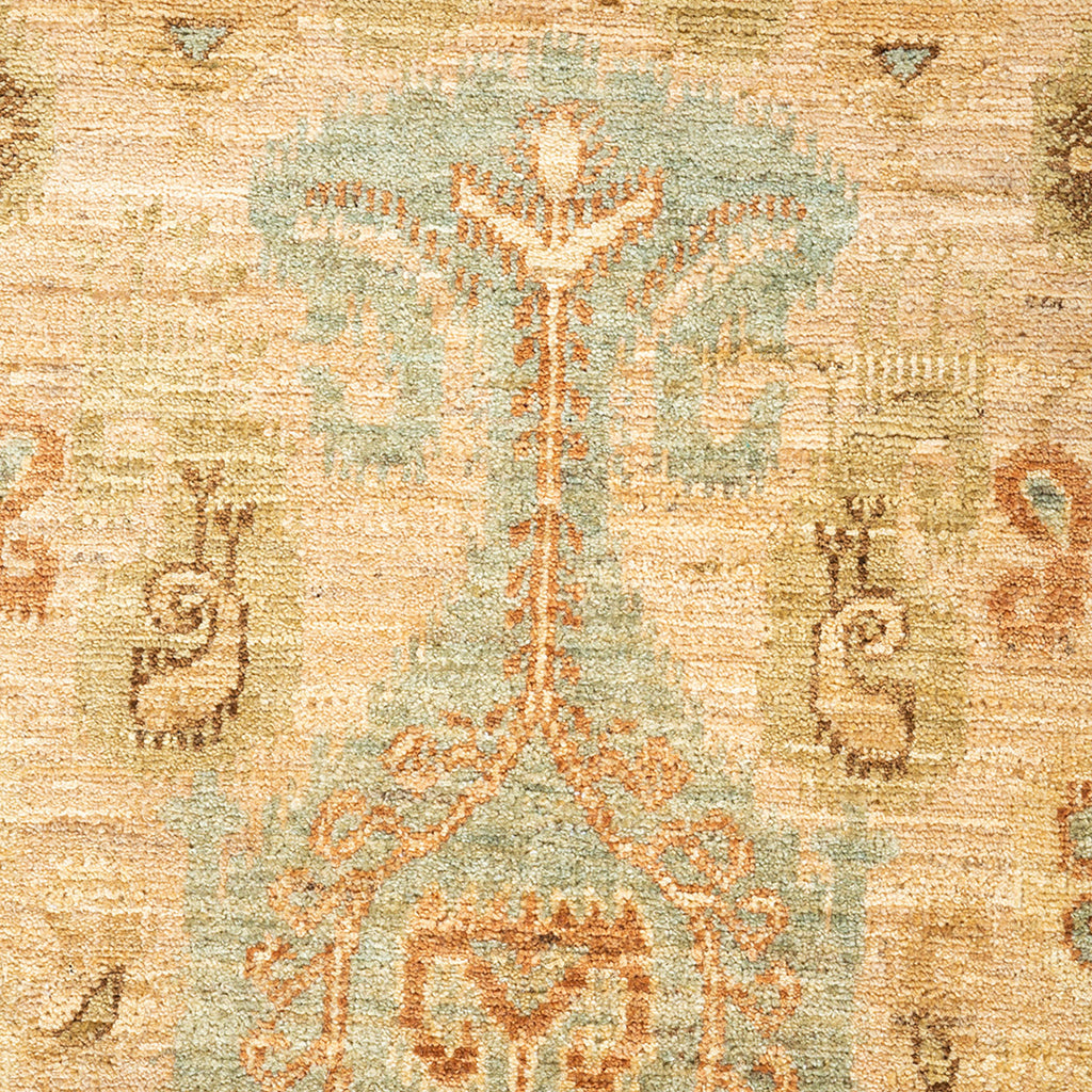 Faded vintage carpet with ornate plant motif in orange and teal.