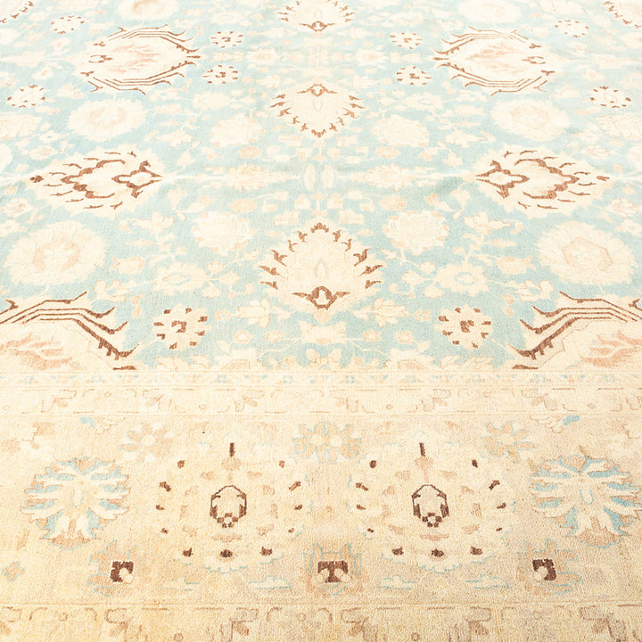 Antique-style carpet with symmetrical floral motifs in soft blue.