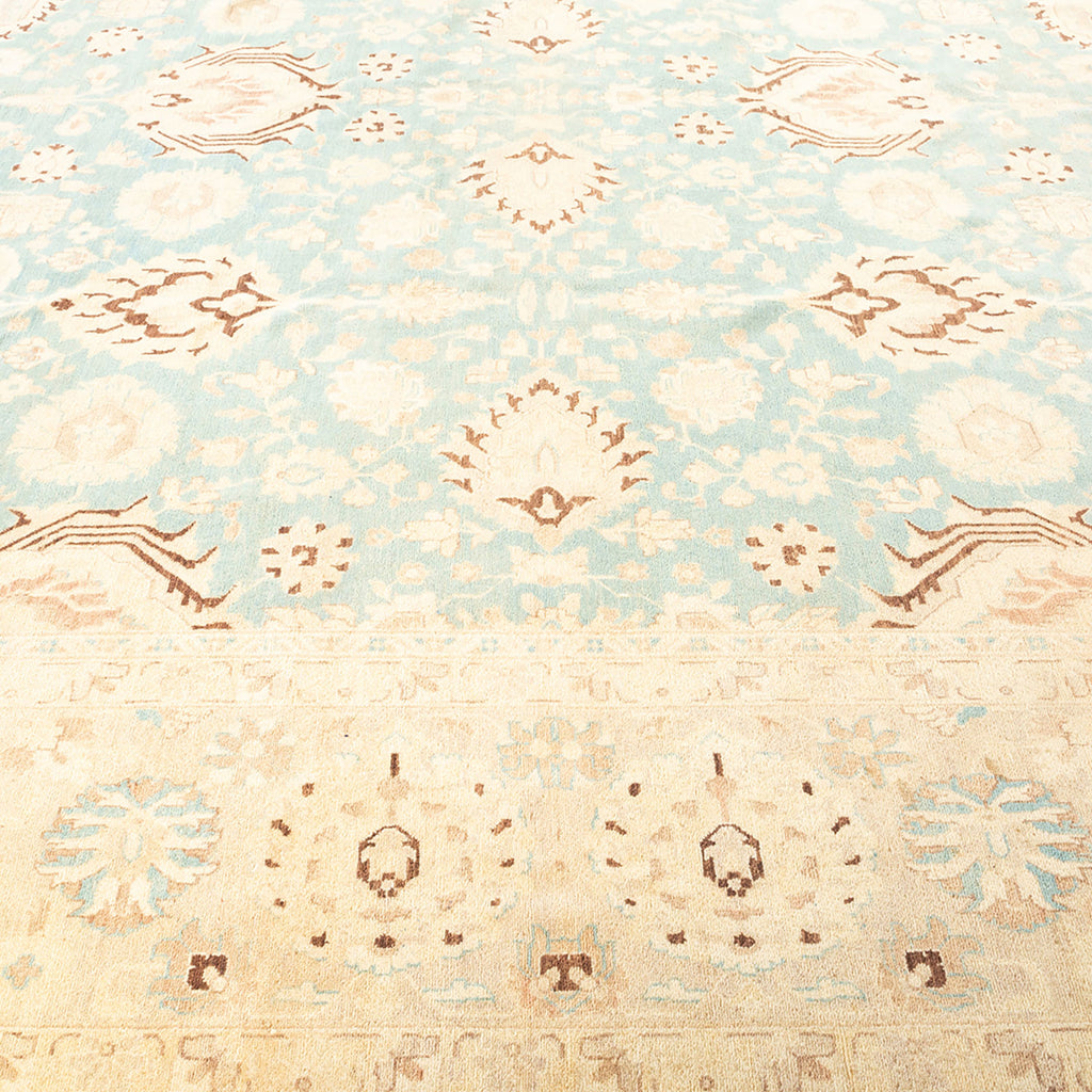Antique-style carpet with symmetrical floral motifs in soft blue.