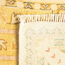 Close-up view of a woven rug with plush texture and pattern in warm yellow and green colors, transitioning to a coarser beige underside with faint traces of pattern.
