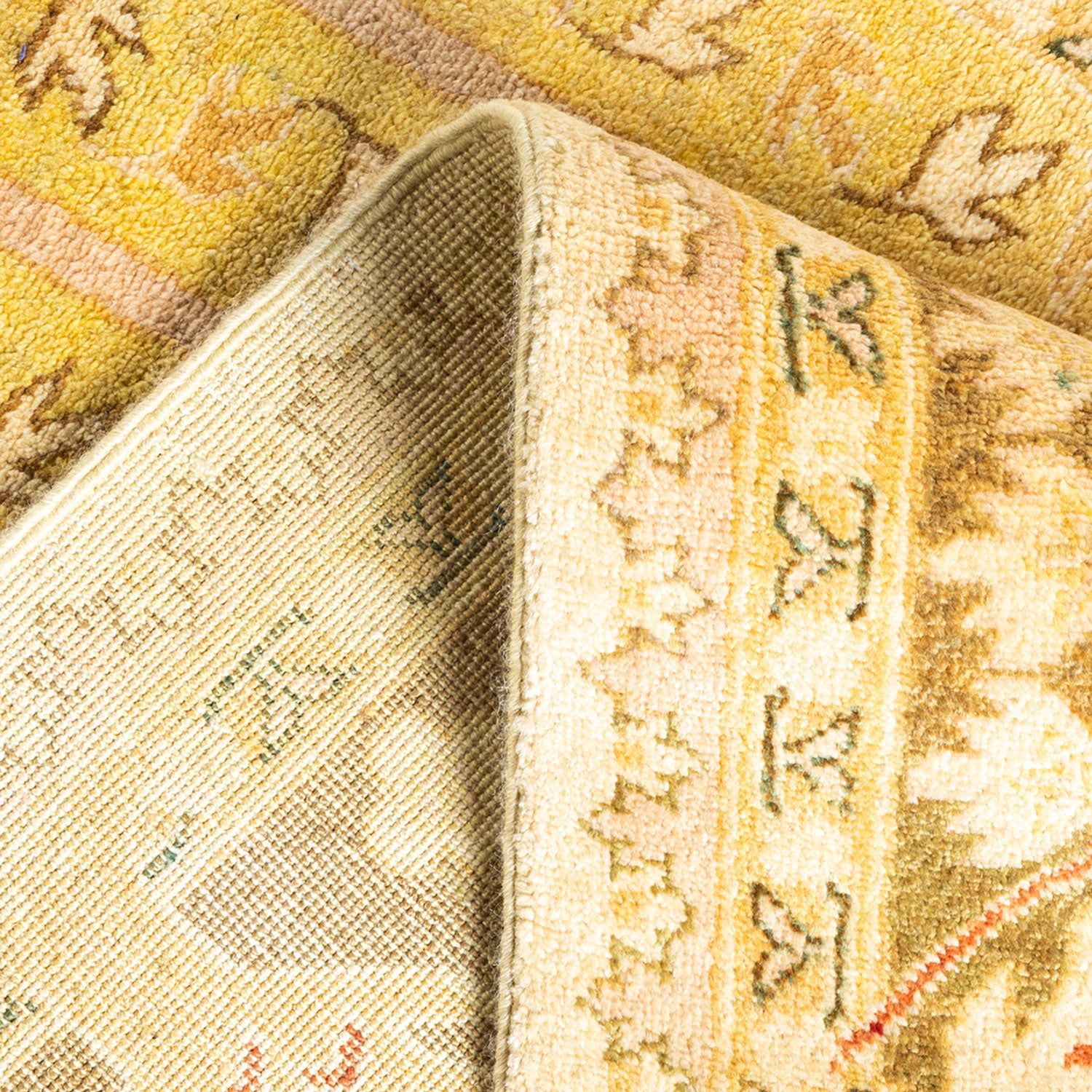 Close-up of a traditional floral rug with folded section revealing pattern and texture.