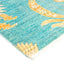Vibrant aqua rug with abstract floral pattern and white fringe.