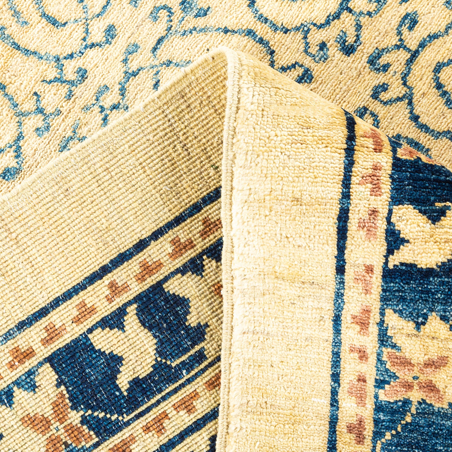 Close-up of folded area rug with intricate traditional floral design.