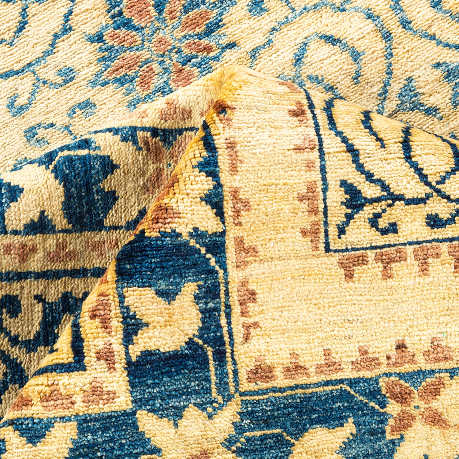 Close-up of a handcrafted rug with intricate patterns in blue and tan.
