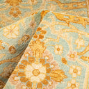 Close-up of a floral and ornate textile with muted colors.