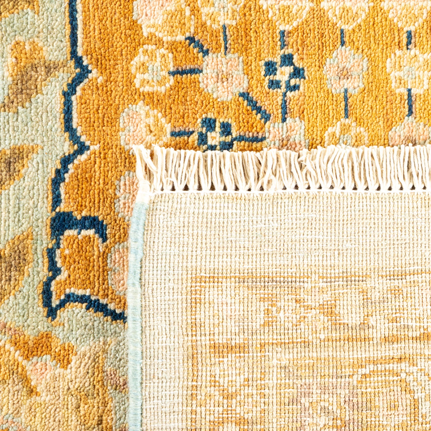 Close-up of a floral patterned rug with orange, blue, and beige shades.