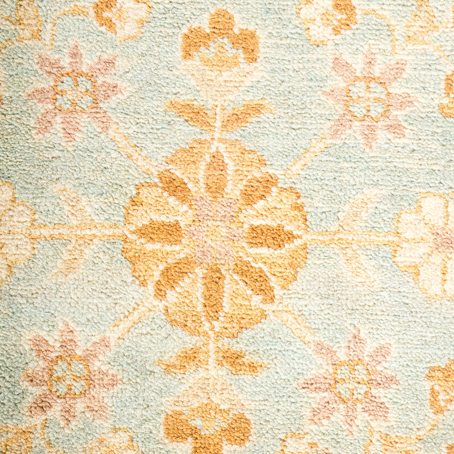Close-up of a floral and symmetrical patterned carpet in soft, elegant colors.