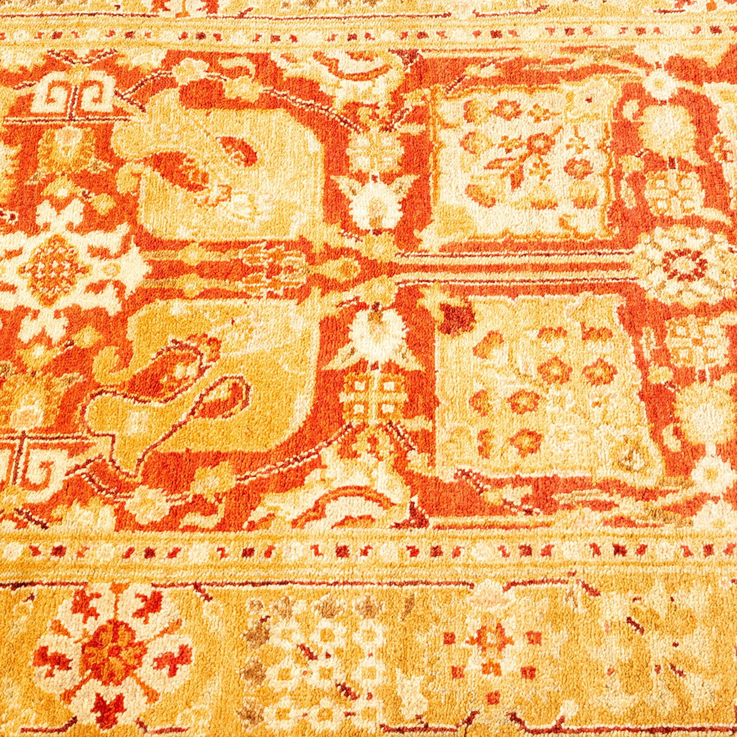 Close-up of an intricate, high-quality traditional patterned carpet in orange and cream with Middle Eastern or South Asian influences.