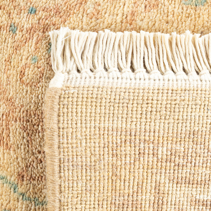 Close-up of a textured beige rug with blue-green dot pattern.