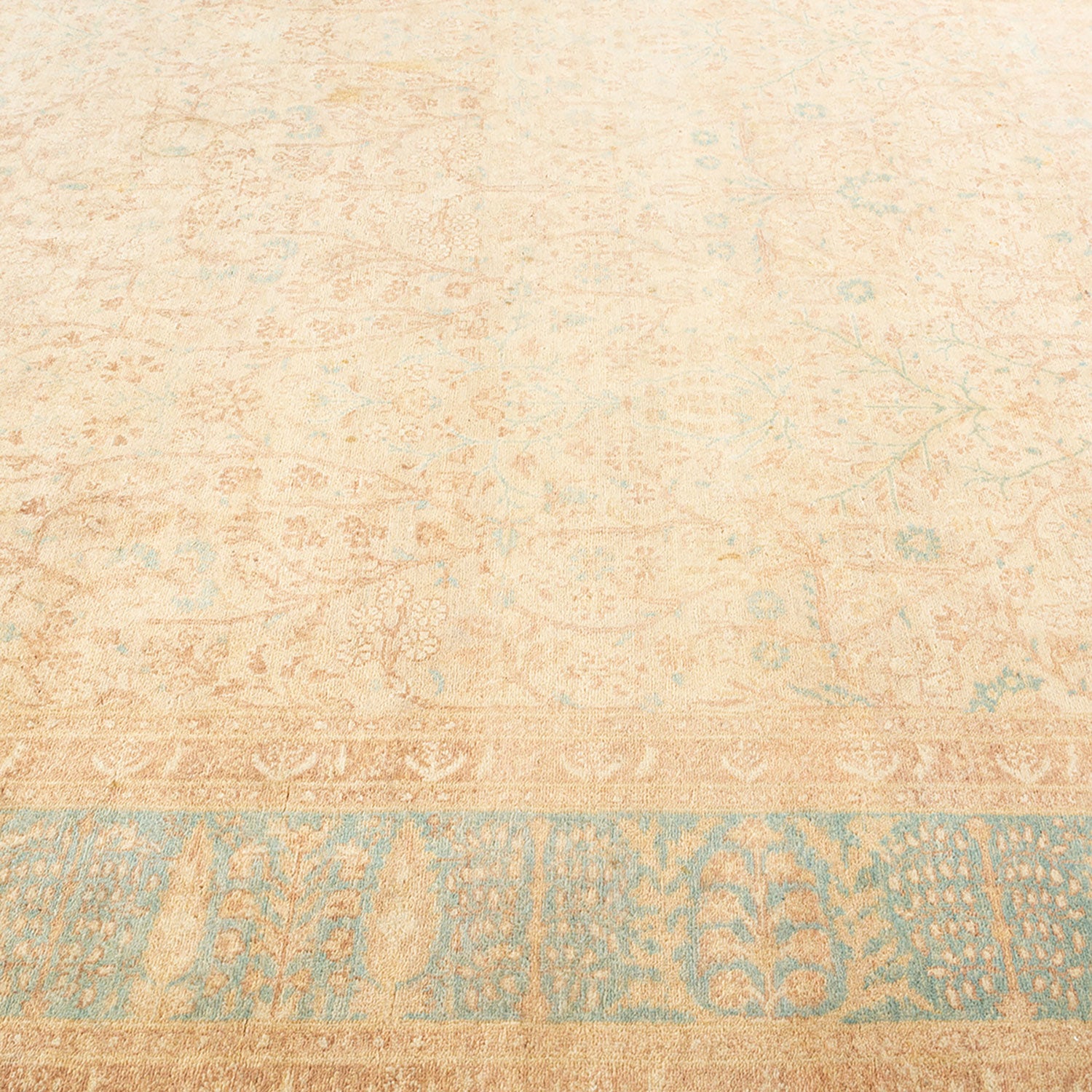 Large weathered vintage rug with faded turquoise and tan designs.