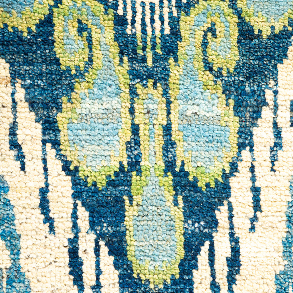 Intricate blue and beige rug with hints of green pattern.