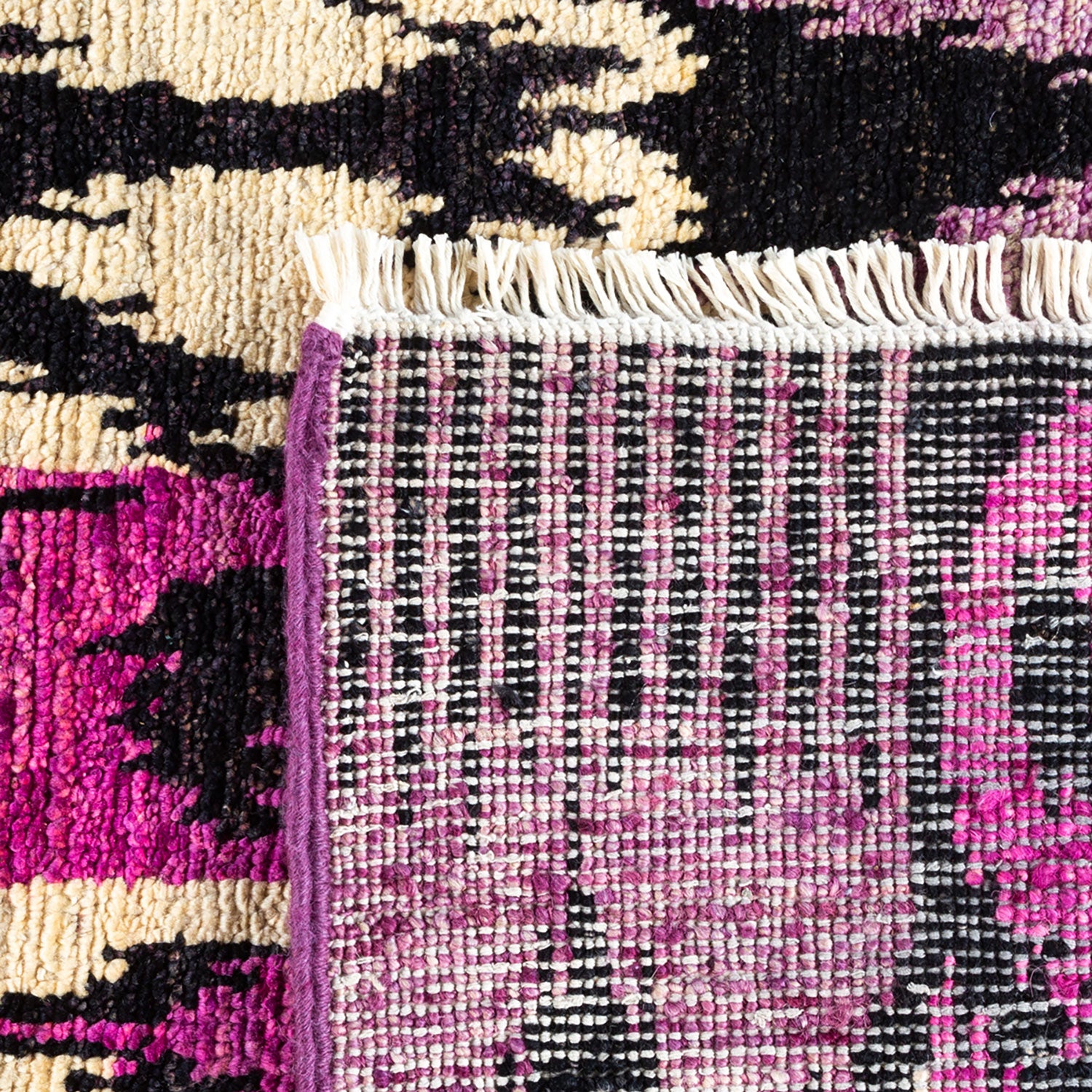 Close-up of a handwoven rug with vibrant geometric patterns and fringe.