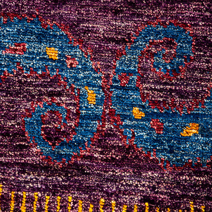 Vibrantly hued textile showcases intricate designs with fringed embellishments.