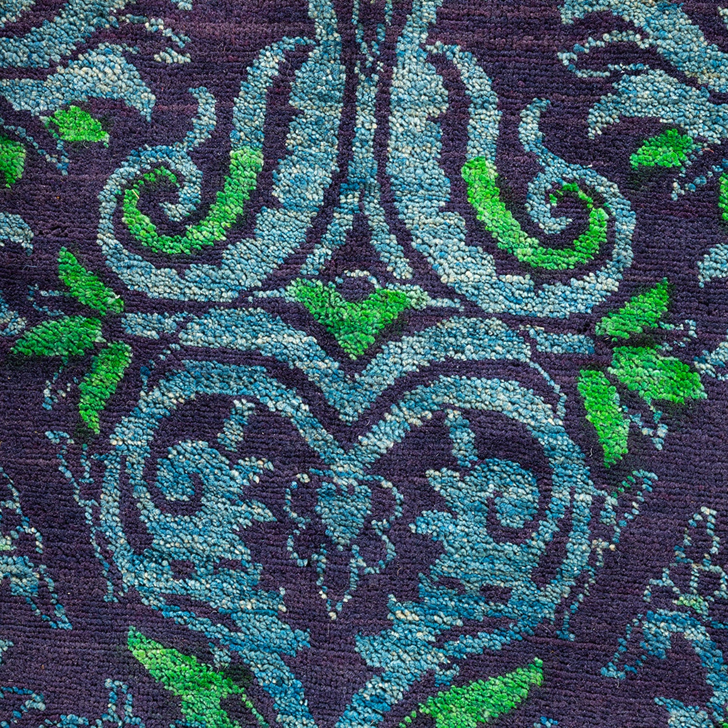 Close-up of intricately embroidered fabric with baroque-inspired blue and green motif.