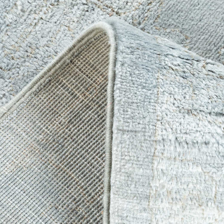 Close-up of a textured, neutral-toned rug with folded edge.