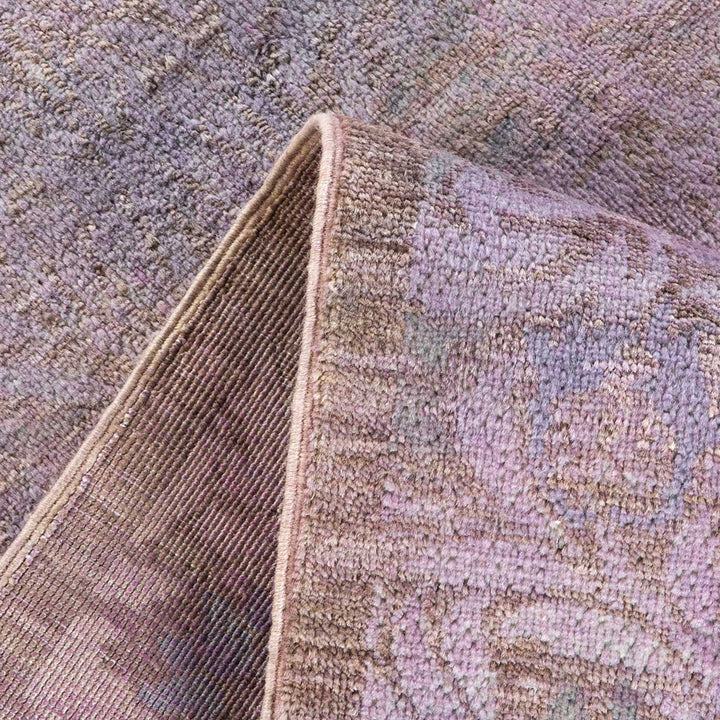 Close-up of a textured, folded rug revealing intricate purple pattern.