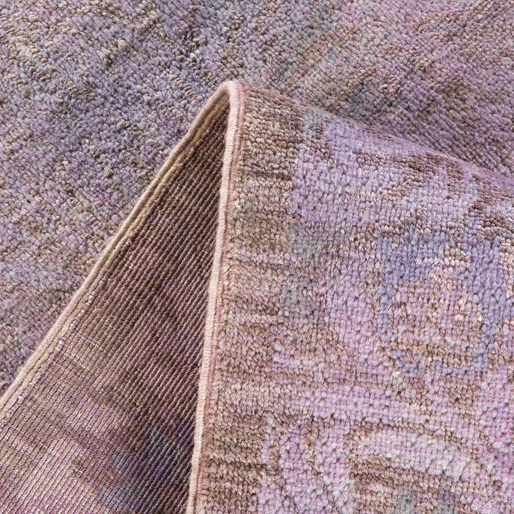 Close-up of a textured, folded rug revealing intricate purple pattern.