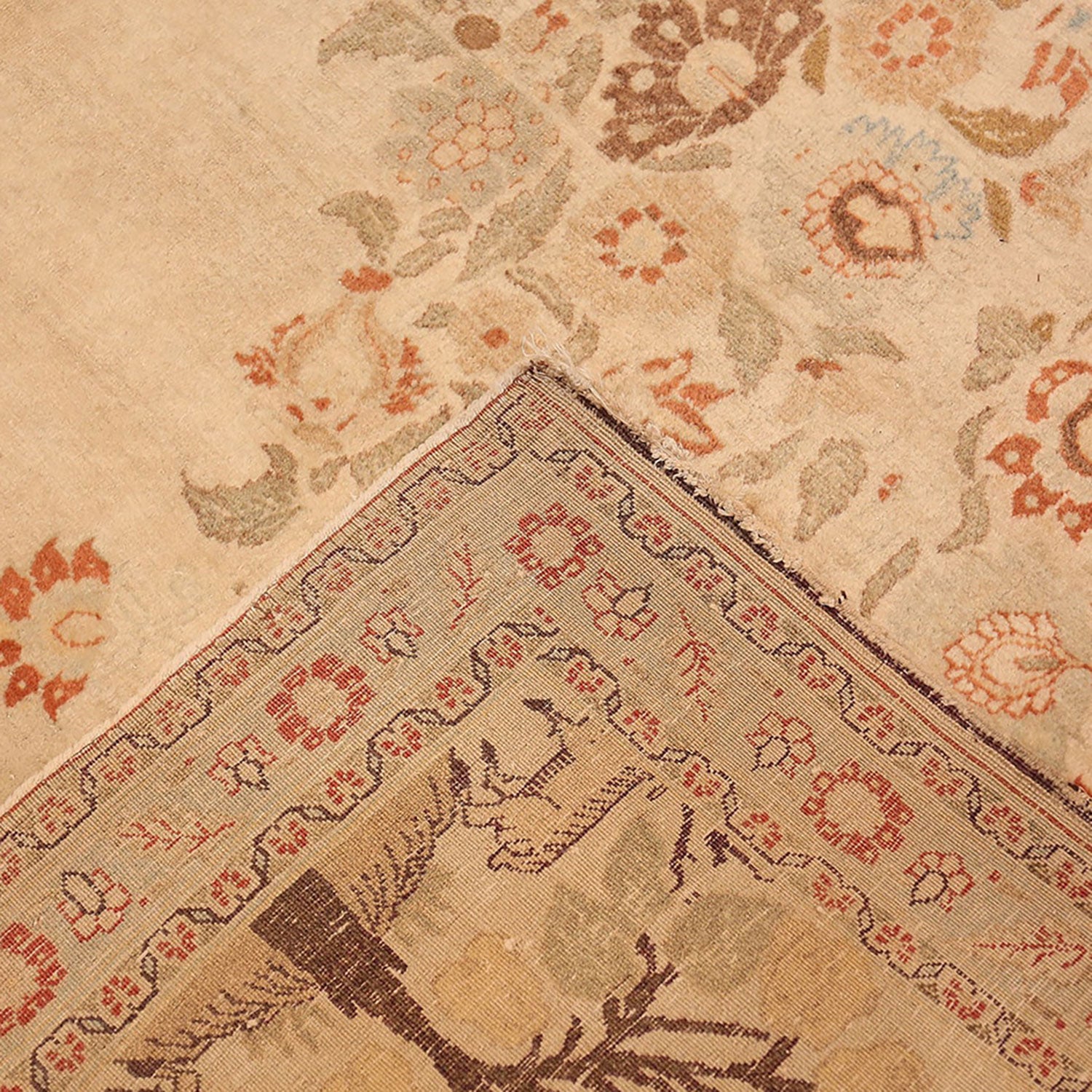 Close-up of a traditional, well-worn rug with intricate floral motifs.