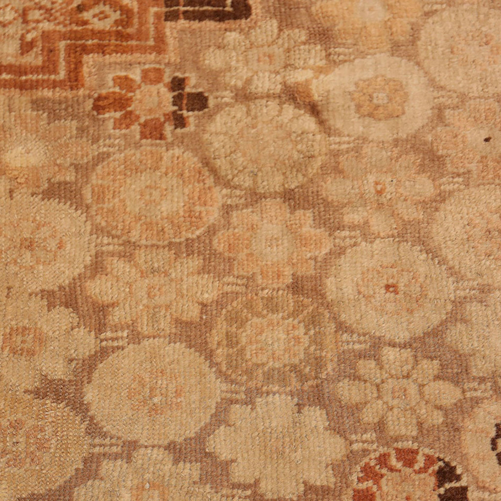 Close-up view of a vintage carpet with intricate geometric-floral pattern.