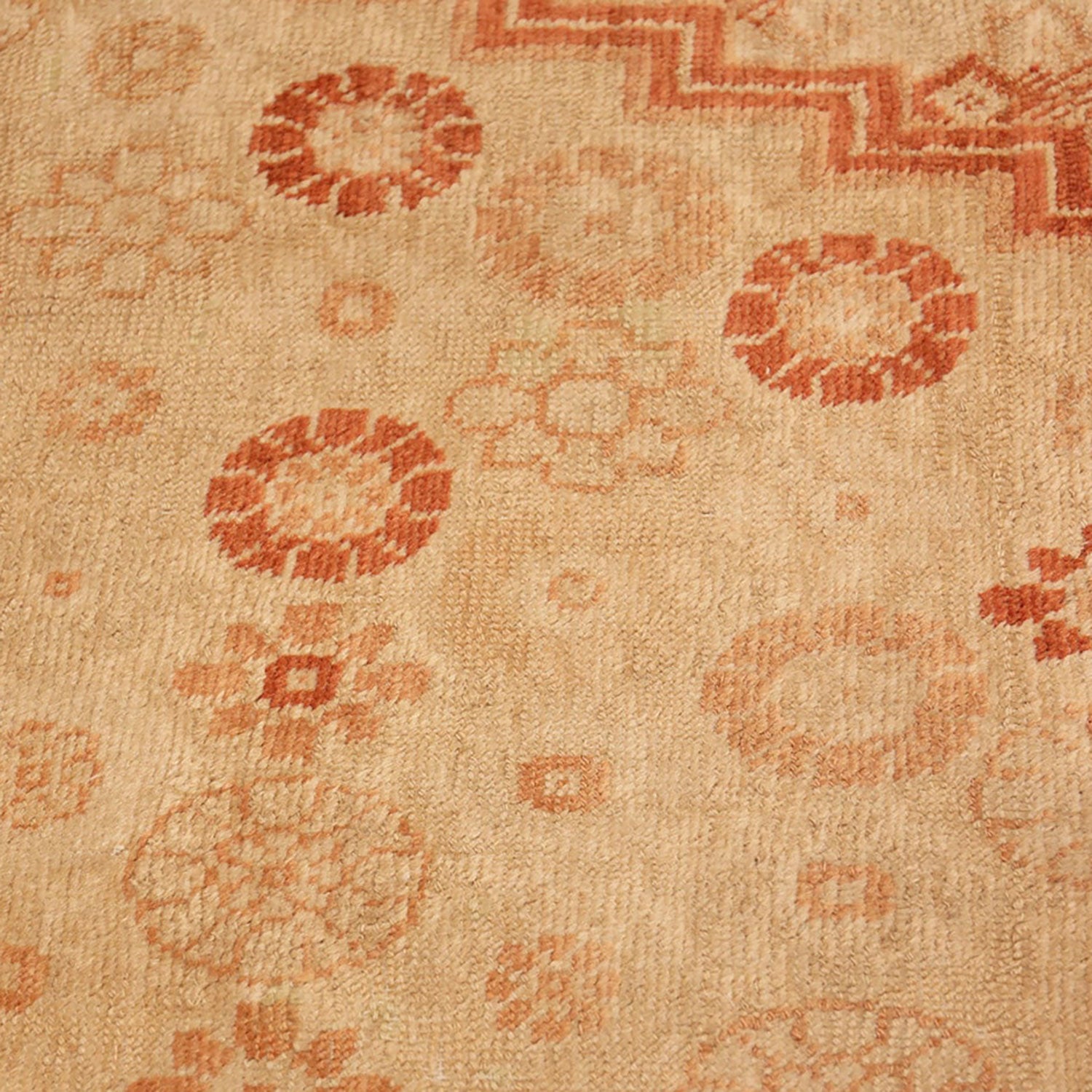Close-up of a hand-woven rug with a symmetrical floral pattern.