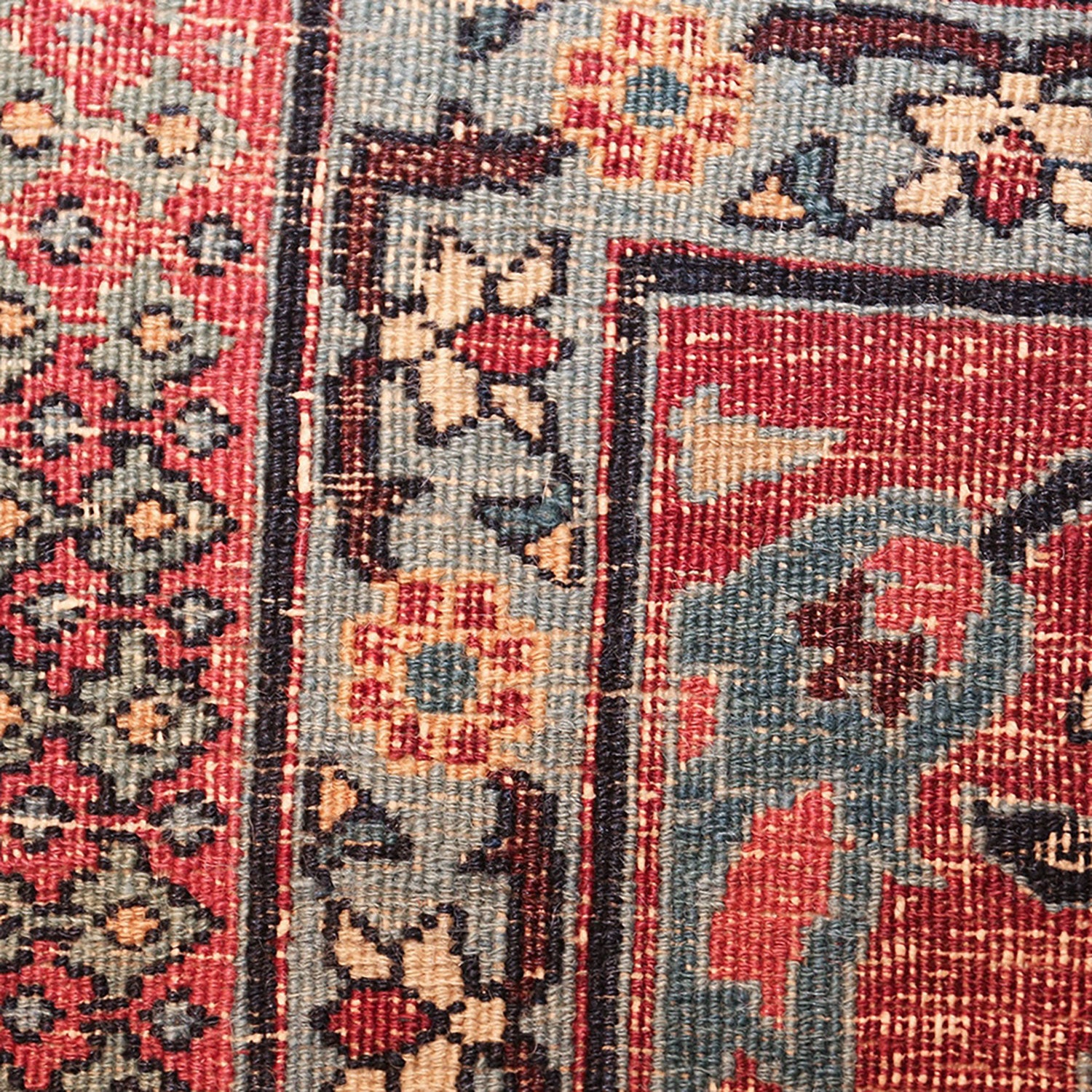 Close-up of a handmade rug with intricate geometric and floral motifs.