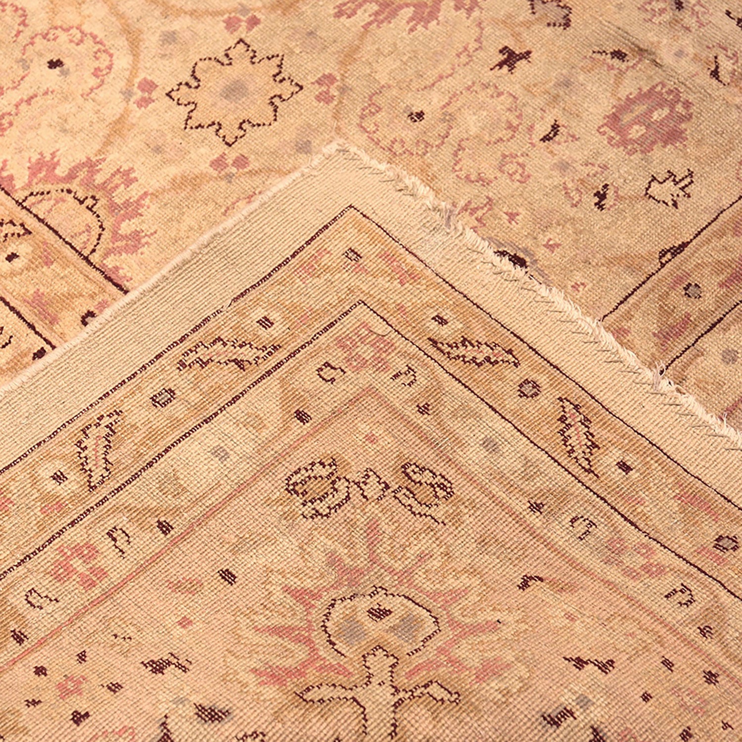 A close-up of a vintage rug with faded geometric and floral patterns.