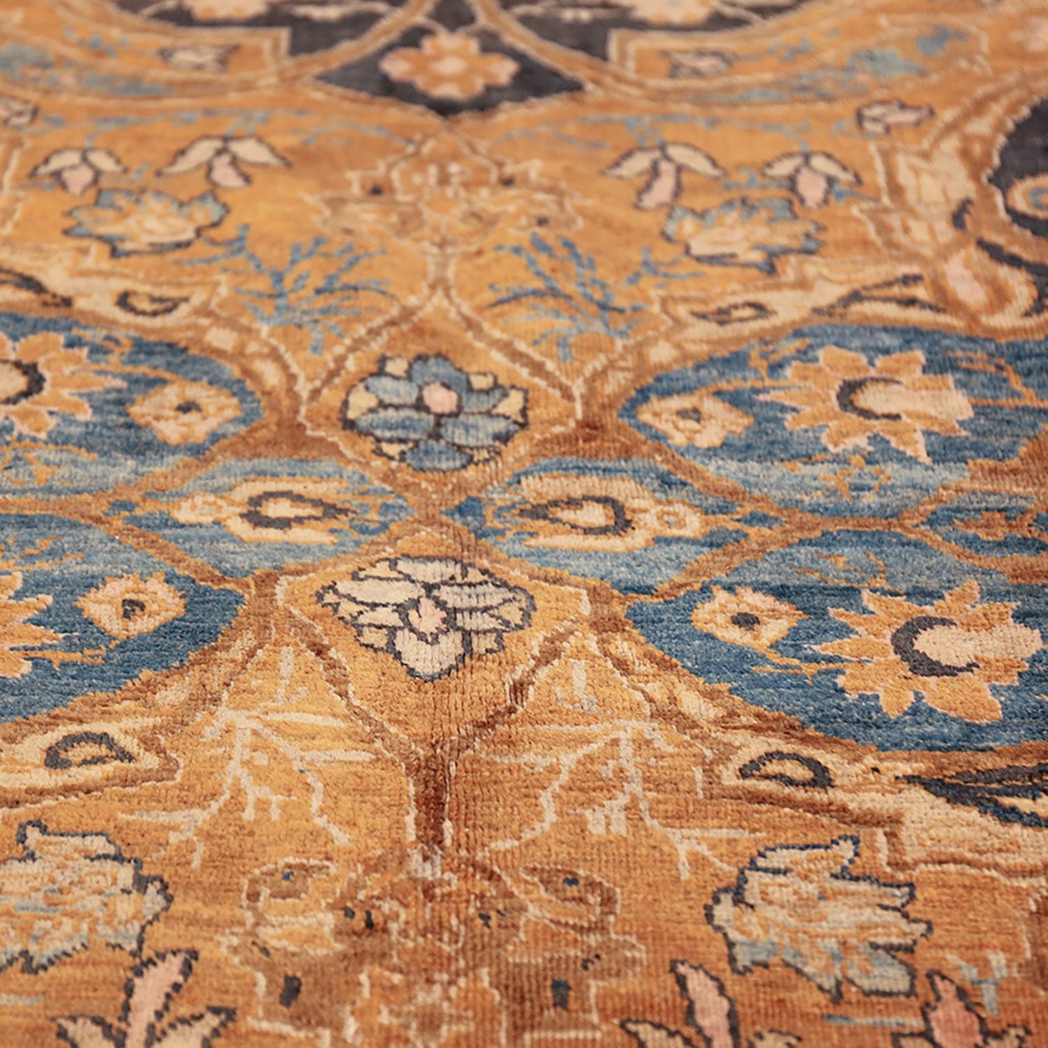 Close-up of a worn, hand-woven carpet with floral pattern