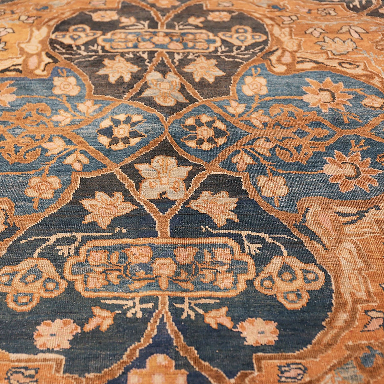 Close-up of an ornate rug featuring intricate floral and geometric motifs in shades of blue and orange.