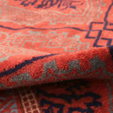 Close-up of vibrant red-orange rug with geometric, abstract pattern.