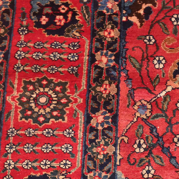 Close-up of a well-worn, intricate Persian rug with floral motifs.