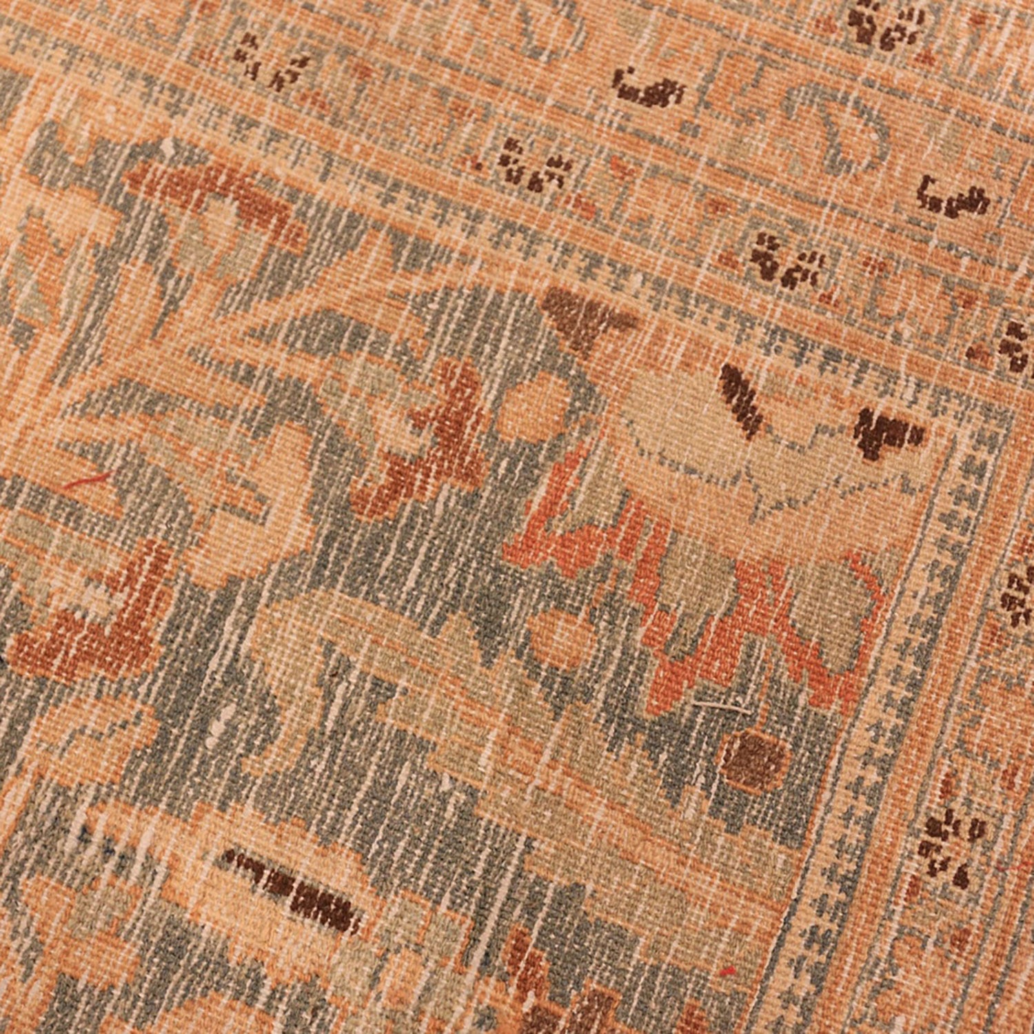 Close-up of weathered patterned carpet with vintage aesthetic in muted colors.