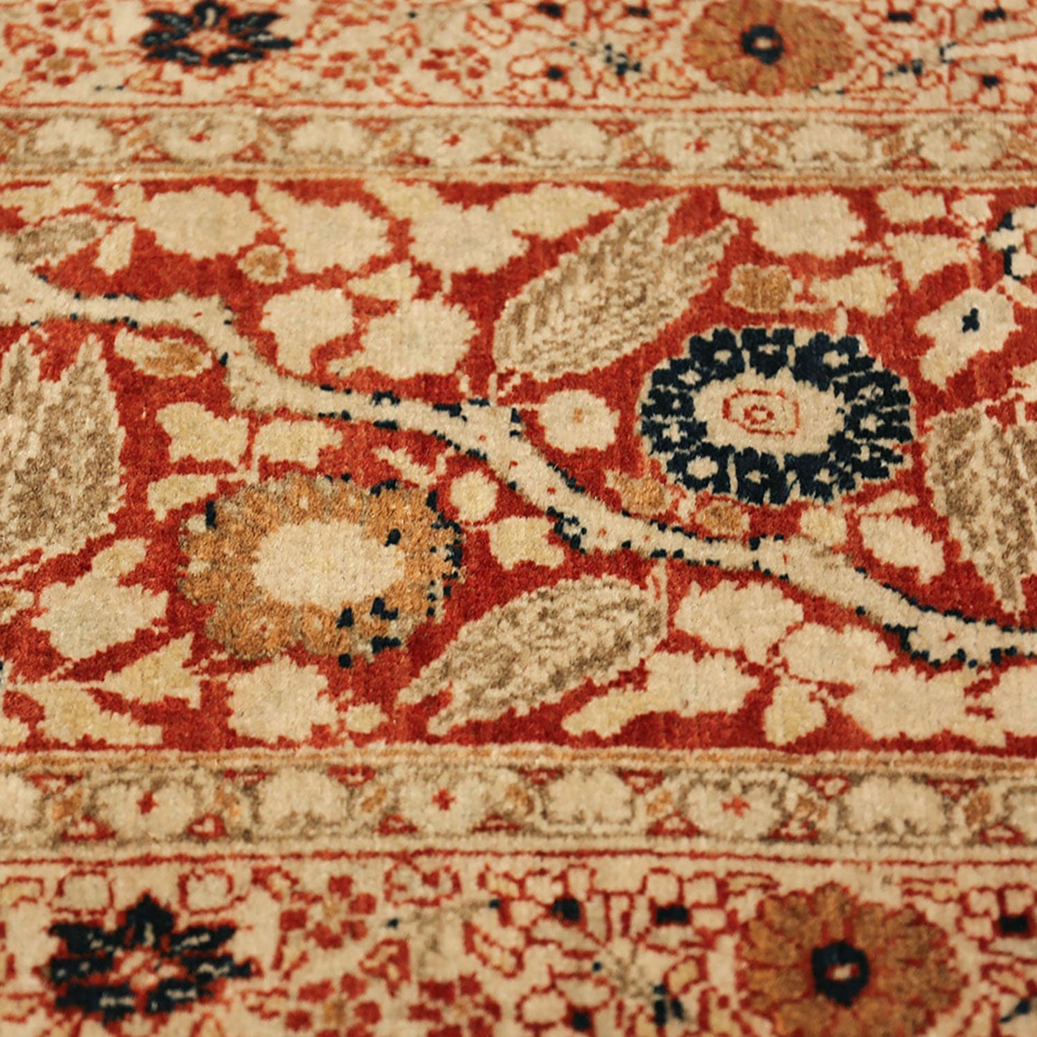 Faded red, beige, and black carpet with intricate floral design.