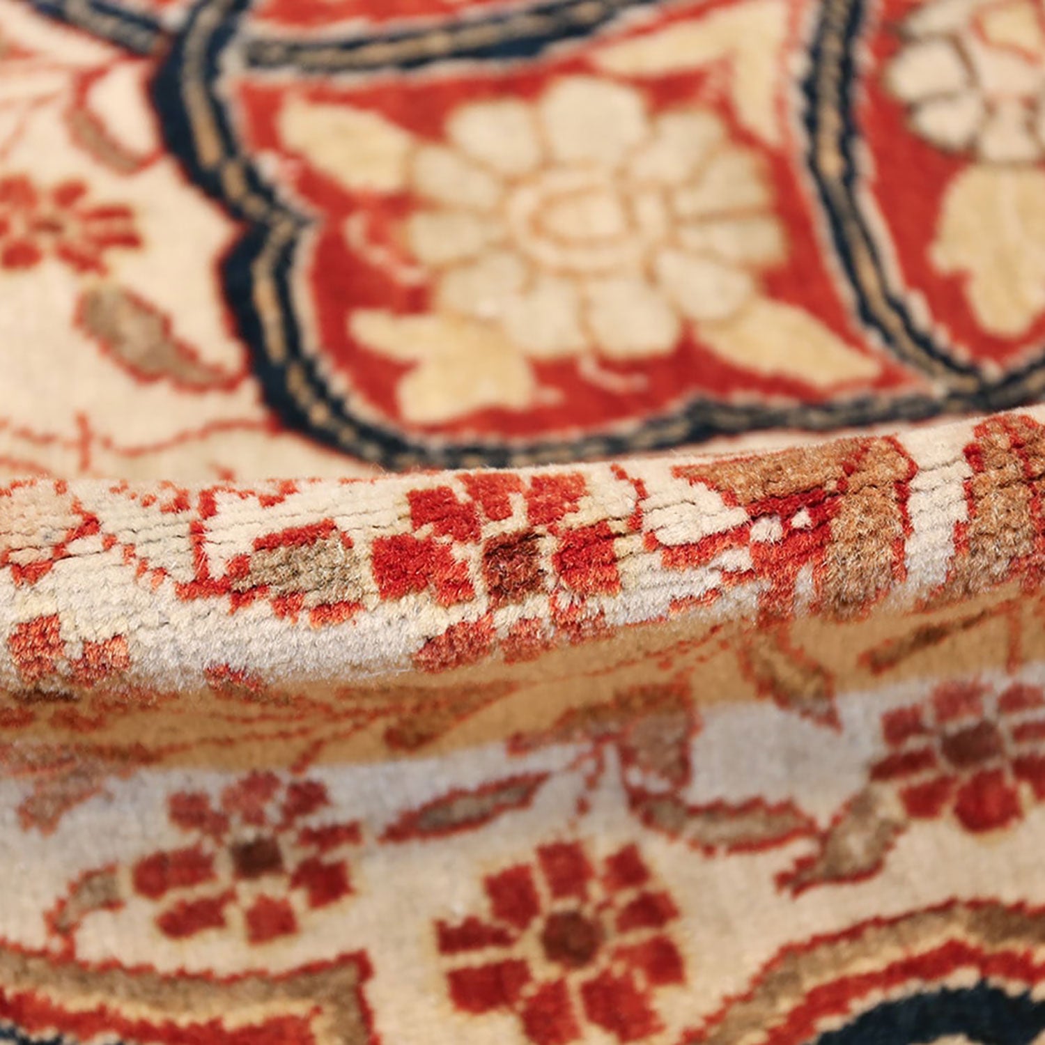Close-up of a rolled-up carpet showcasing intricate floral motifs.