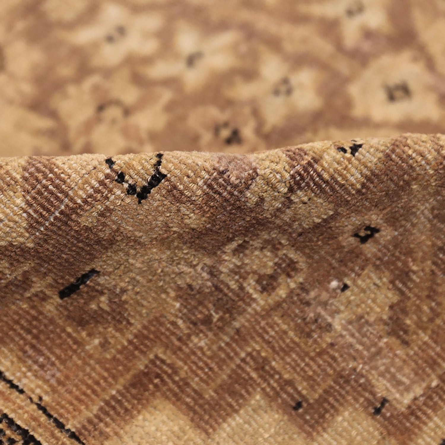 Close-up of textured fabric with brown and tan hues, showing wear.