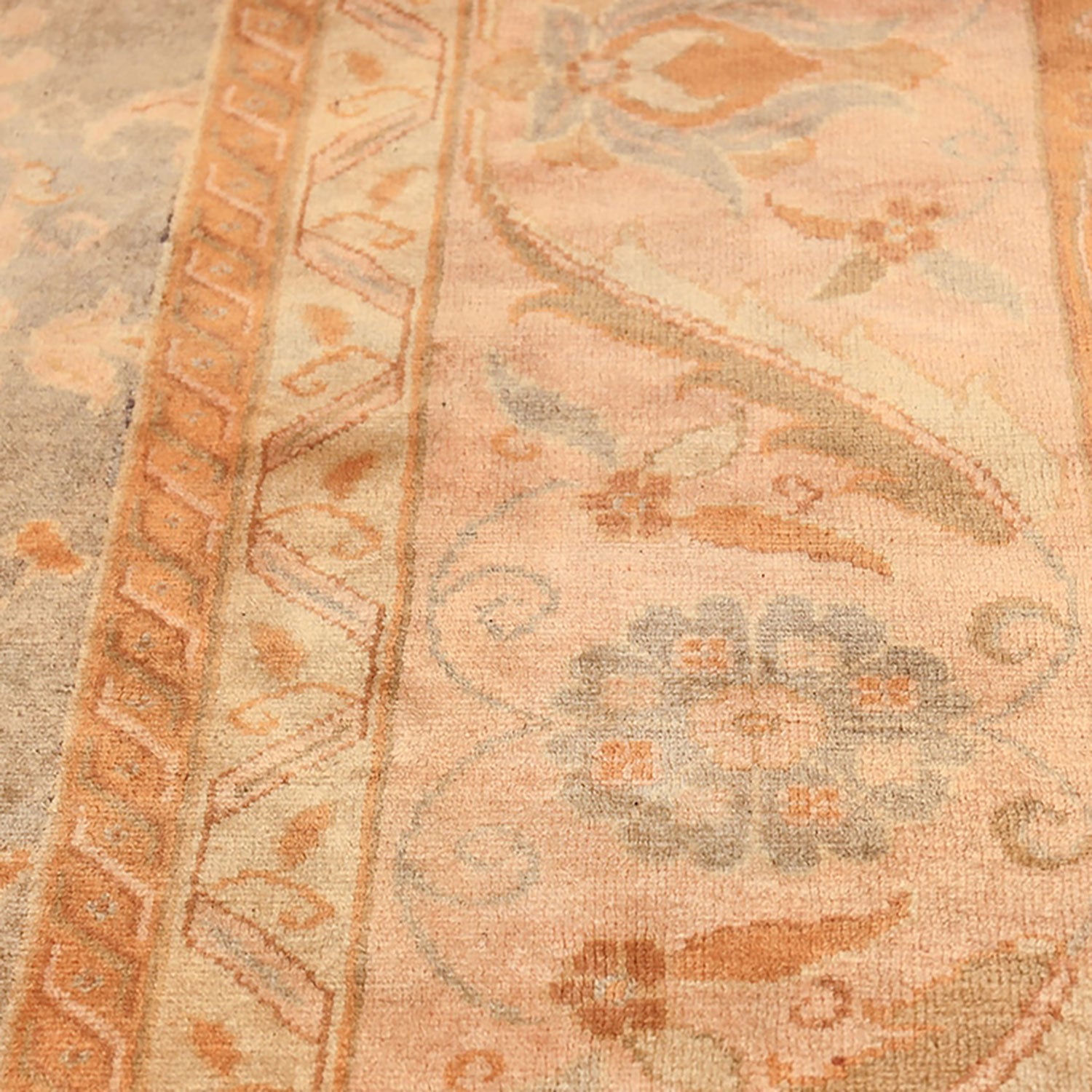Vintage-style carpet with geometric border and faded floral motif.
